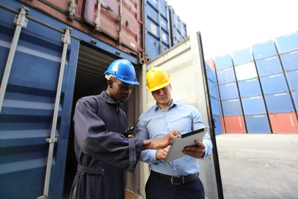 Engineer or supervisor checking and control loading Containers box from Cargo at harbor.Foreman control Industrial Container Cargo freight ship at industry.Transportation and logistic concept.